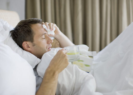 Man sick in bed drinking water