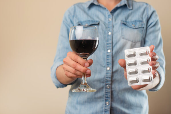 woman holding alcohol and antibiotic pill pack